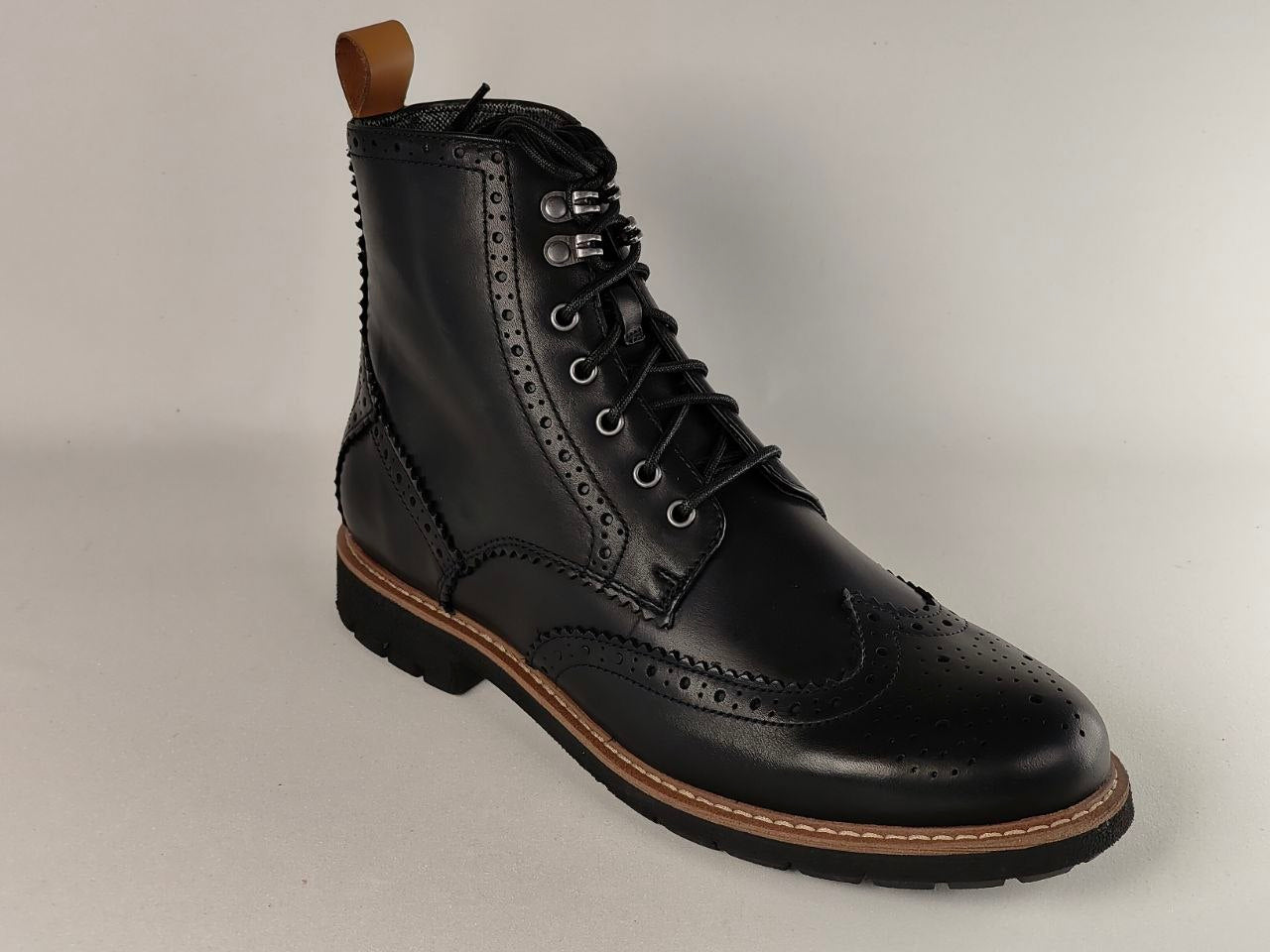 Black leather boot with brown sole on a light gray background