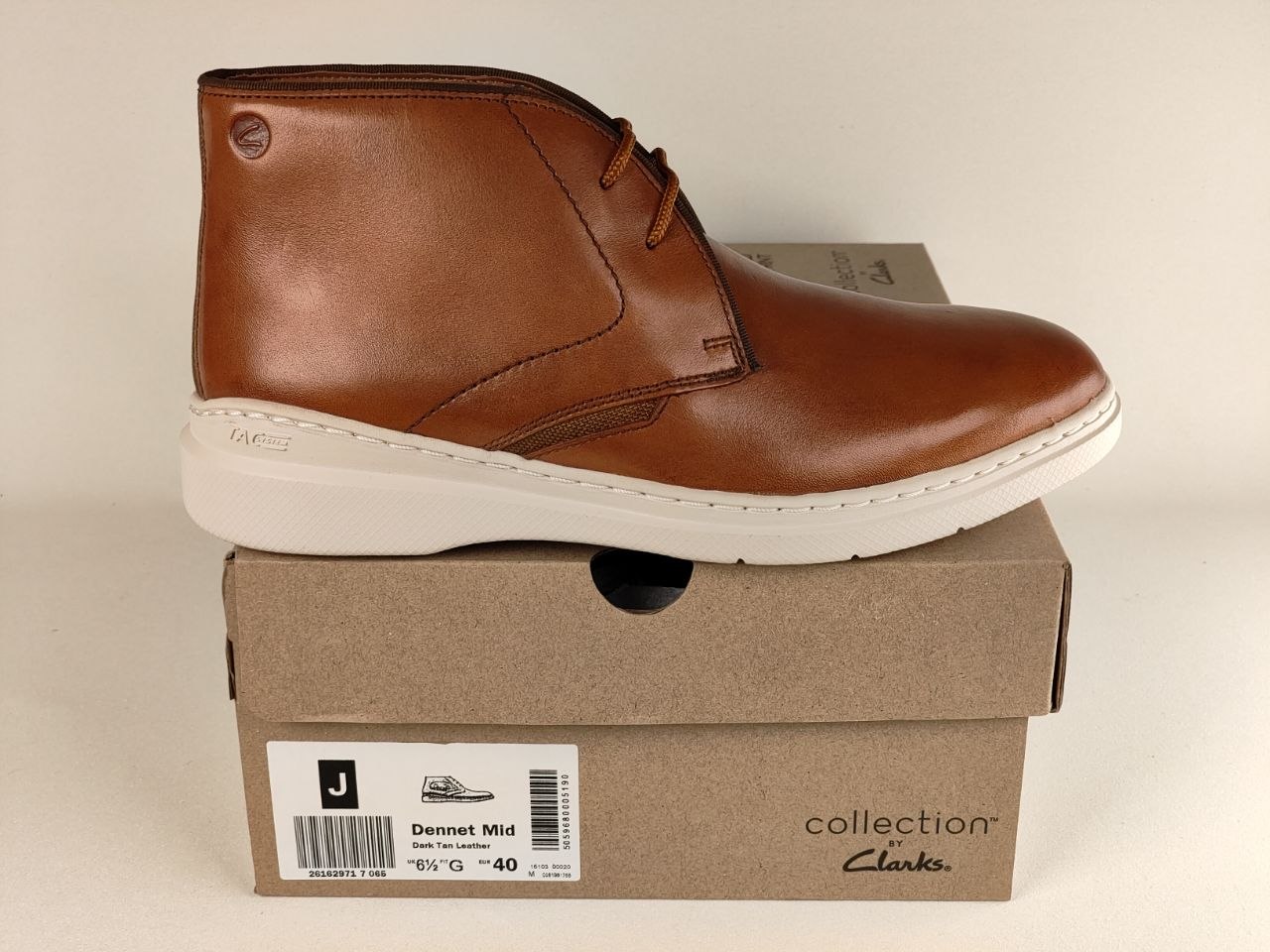 Brown leather shoe on a Clarks shoe box with a beige background