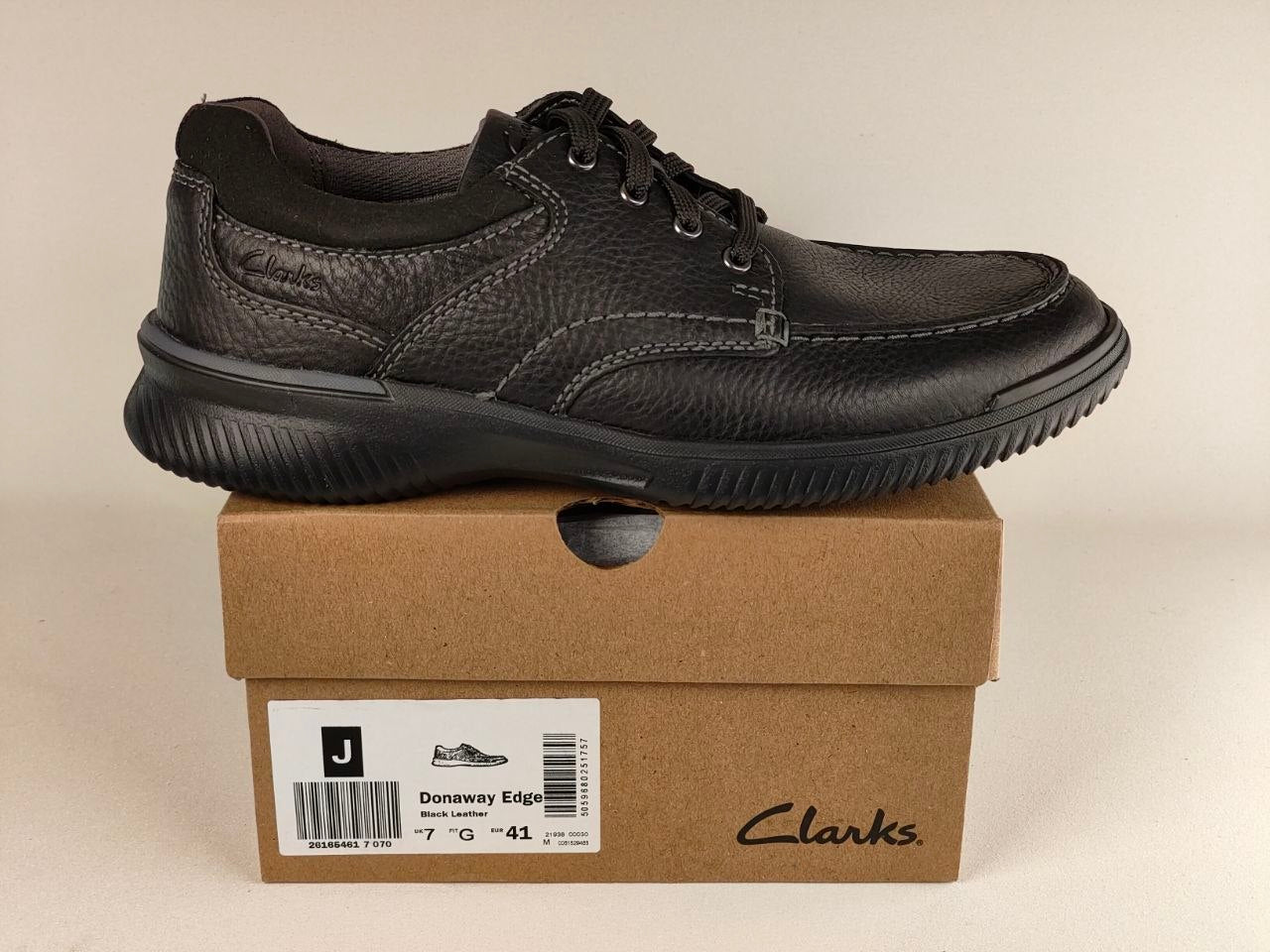 Black leather shoe on a Clarks box with a beige background