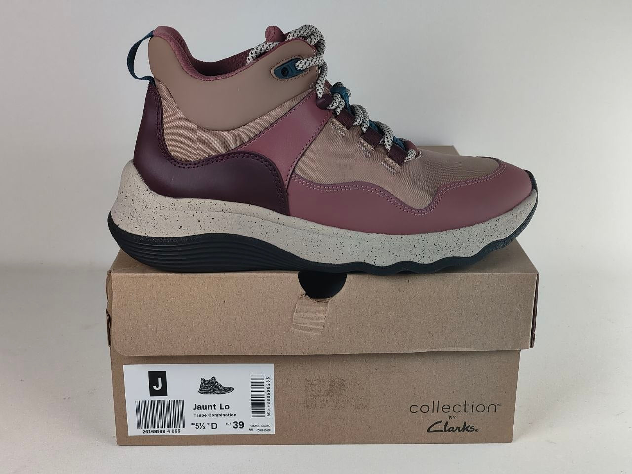 A Jumps Leaping sneaker in dusty rose and beige with dark purple accents, resting on its brown cardboard shoebox. The shoebox features the 'collection Clark' logo and a size label for 'Jumps Leaping'.