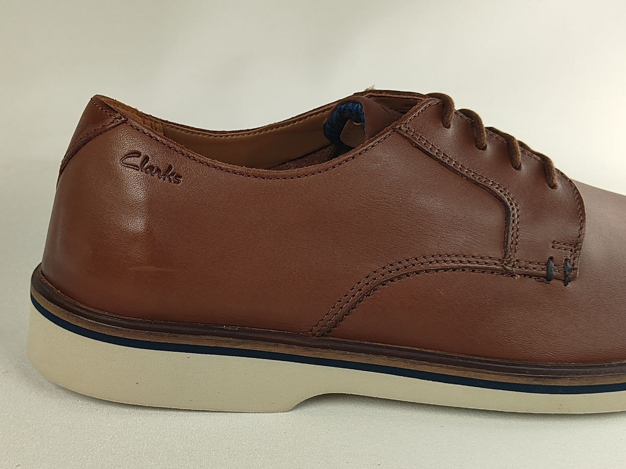 Brown leather shoe with white sole on a light background
