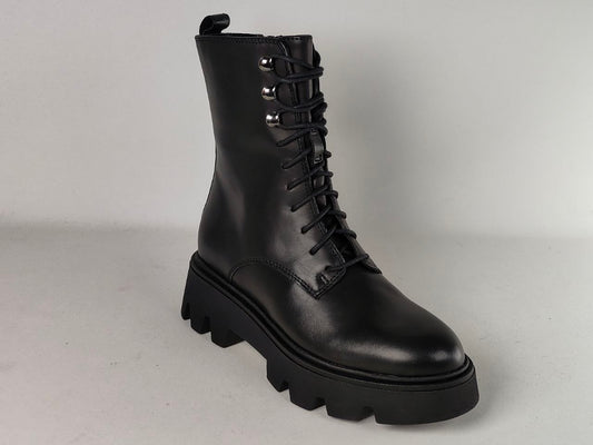 A single black leather lace-up ankle boot with a chunky lug sole and silver metal eyelets, photographed on a light gray studio background.