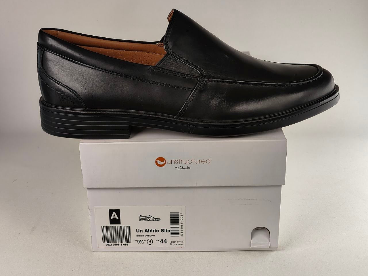 Black loafer shoe on a white box with 'Unstructured' branding