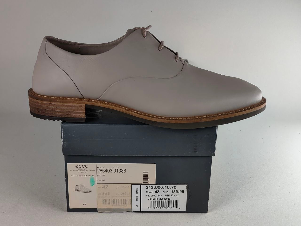 A light gray leather lace-up dress shoe by ECCO, displayed in profile on top of its dark gray retail box against a neutral light gray background.