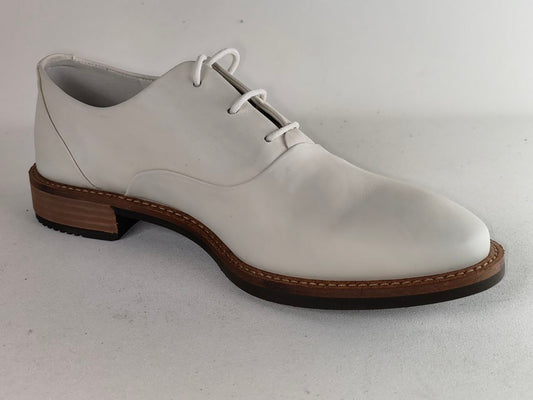 A white leather oxford-style dress shoe with white laces, a brown stacked block heel, and a dark brown outsole, shown on a light gray background.