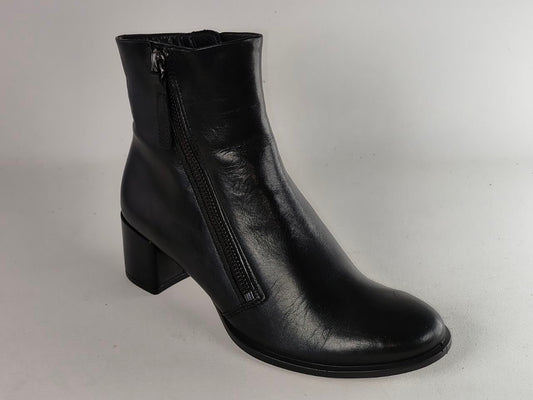 A black leather ankle boot with a side zipper, low block heel, and rounded toe, photographed against a neutral light gray background.
