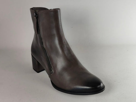 A dark brown leather ankle boot with a side zipper, block heel, and rounded toe, photographed against a neutral light gray background.