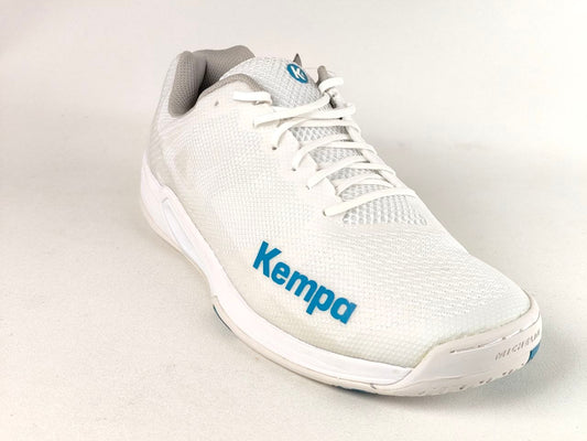 A white Kempa athletic shoe with a white mesh upper, white laces, a white sole, and blue branding on the side, photographed on a light gray background.