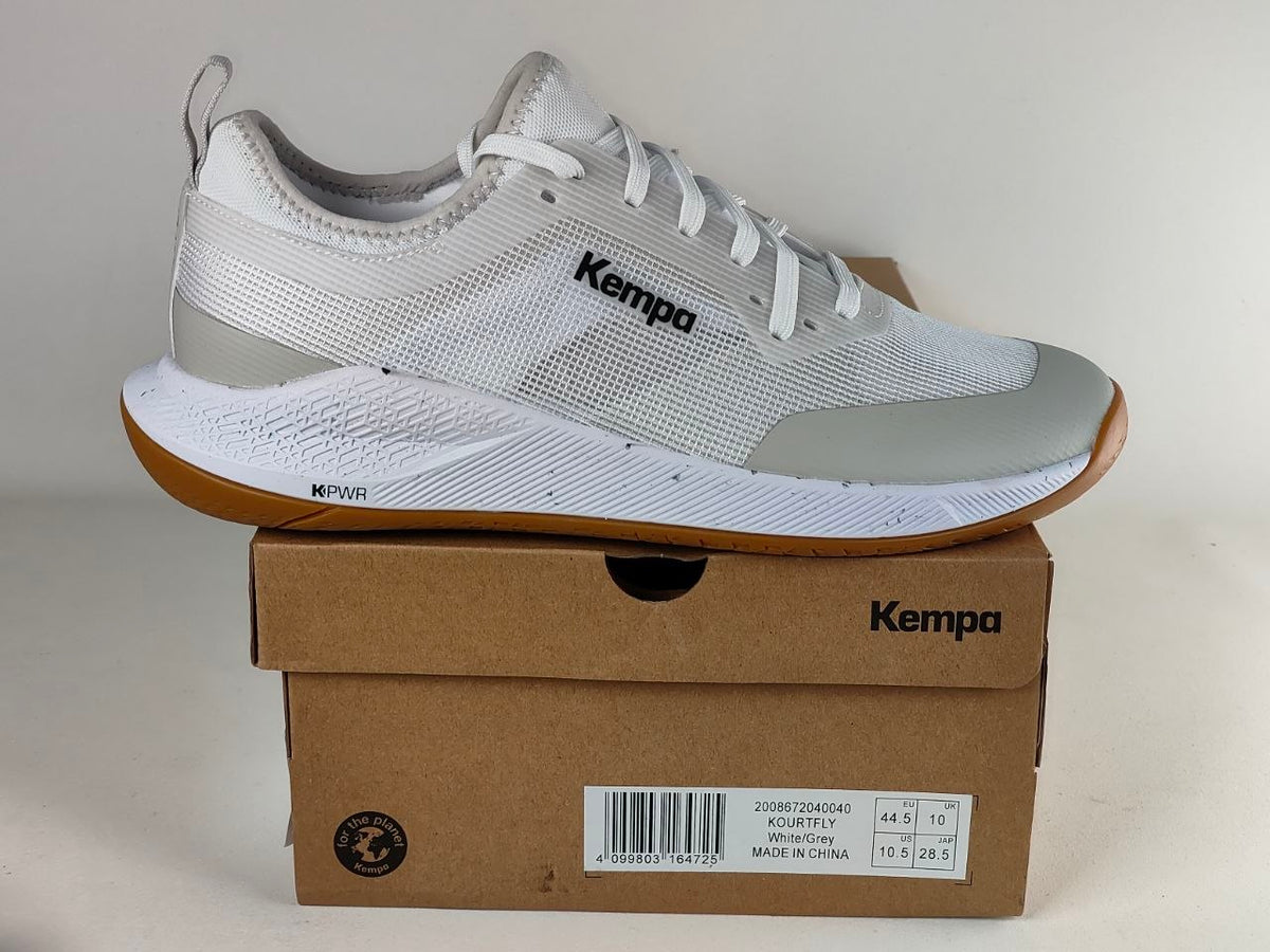 A white and light gray Kempa running shoe resting on top of its brown cardboard shoebox against a neutral light gray background.