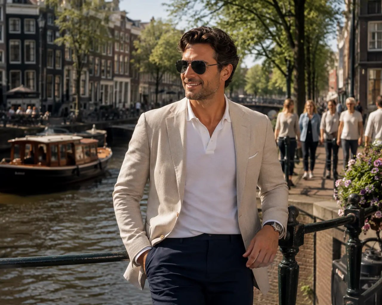 Man in a beige blazer and Next Aviator Sunglasses Silver Frame Dark Grey Lensstanding by a canal with boats and people in the background.
