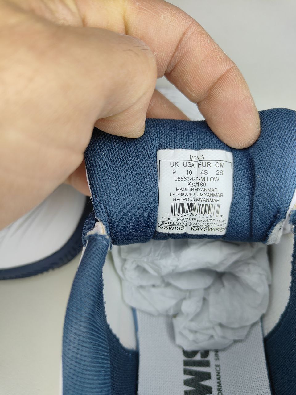 Close-up of a shoe label held by a hand, with a blurred background