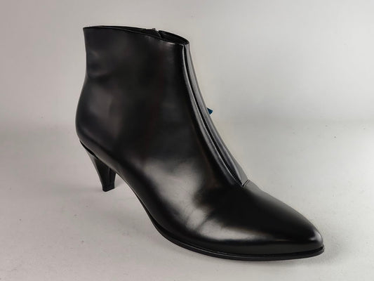 A black leather ankle boot with a pointed toe and a slim kitten heel, photographed against a neutral light gray background.