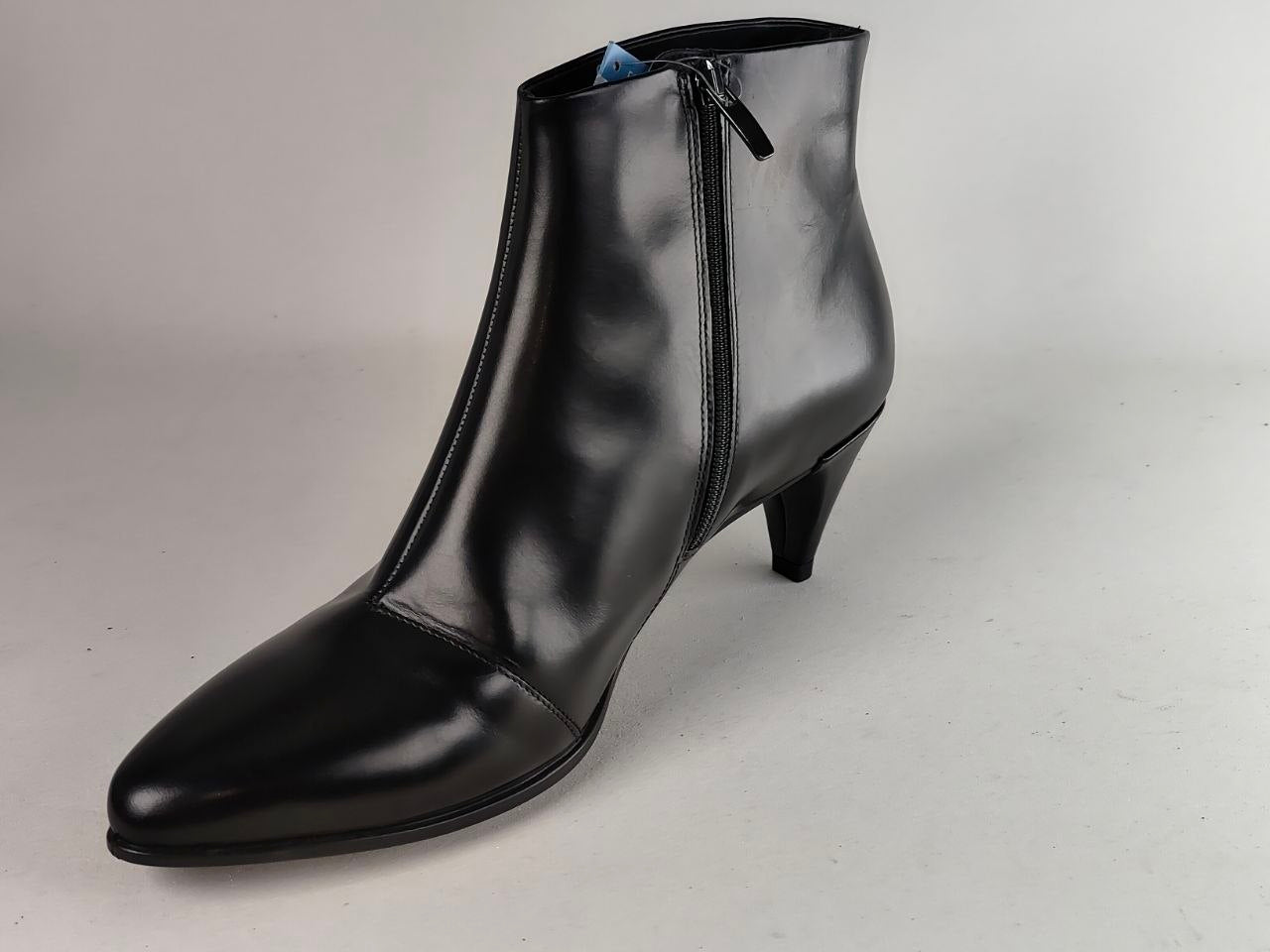 A single black leather ankle boot with a pointed toe, kitten heel, and side zipper, photographed on a neutral light gray background.
