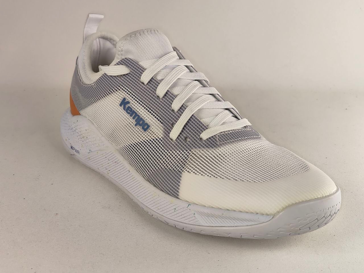 A white and gray mesh athletic sneaker with white laces, a white sole, and a small orange accent near the heel, photographed on a plain light background.