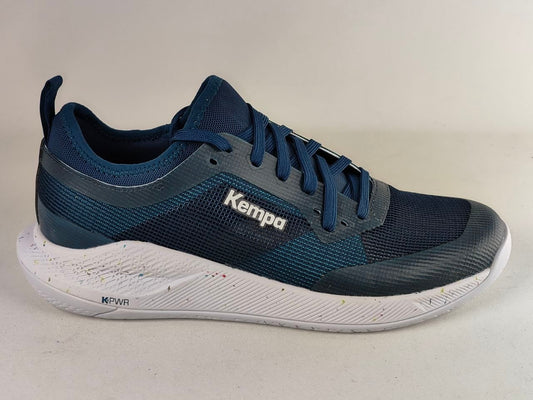 A single Kempa athletic sneaker in navy blue and dark gray mesh with a white sole, photographed on a neutral light beige background.