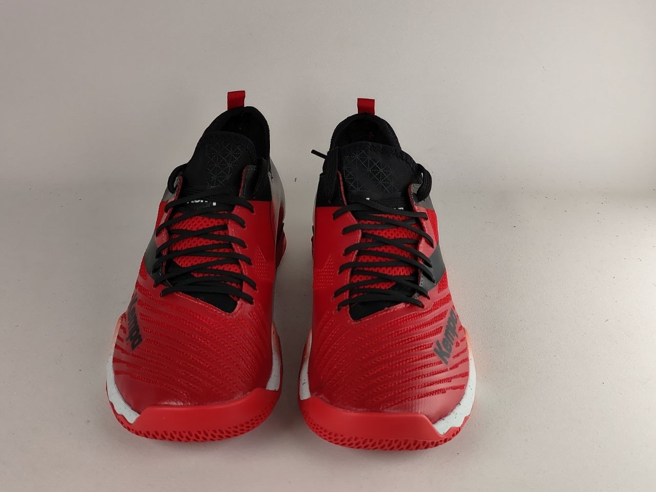 A pair of red and black athletic sneakers photographed from the front on a plain light background.