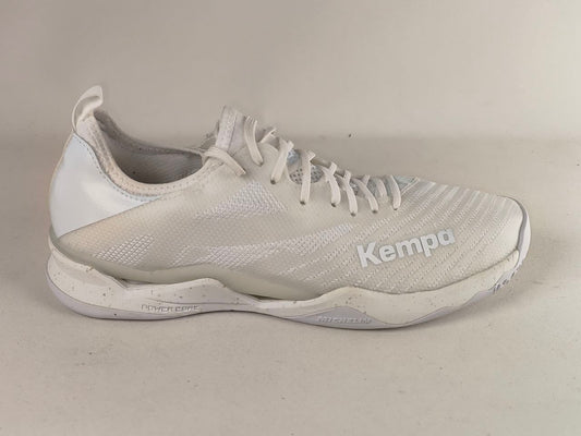 A white Kempa athletic shoe with a textured mesh upper, white laces, and a white sole, photographed against a neutral light beige background.