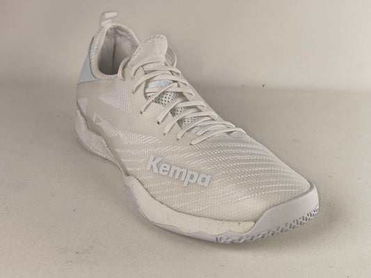 A white and light gray Kempa athletic shoe with a textured mesh upper, white laces, and a white sole, photographed on a neutral beige background.