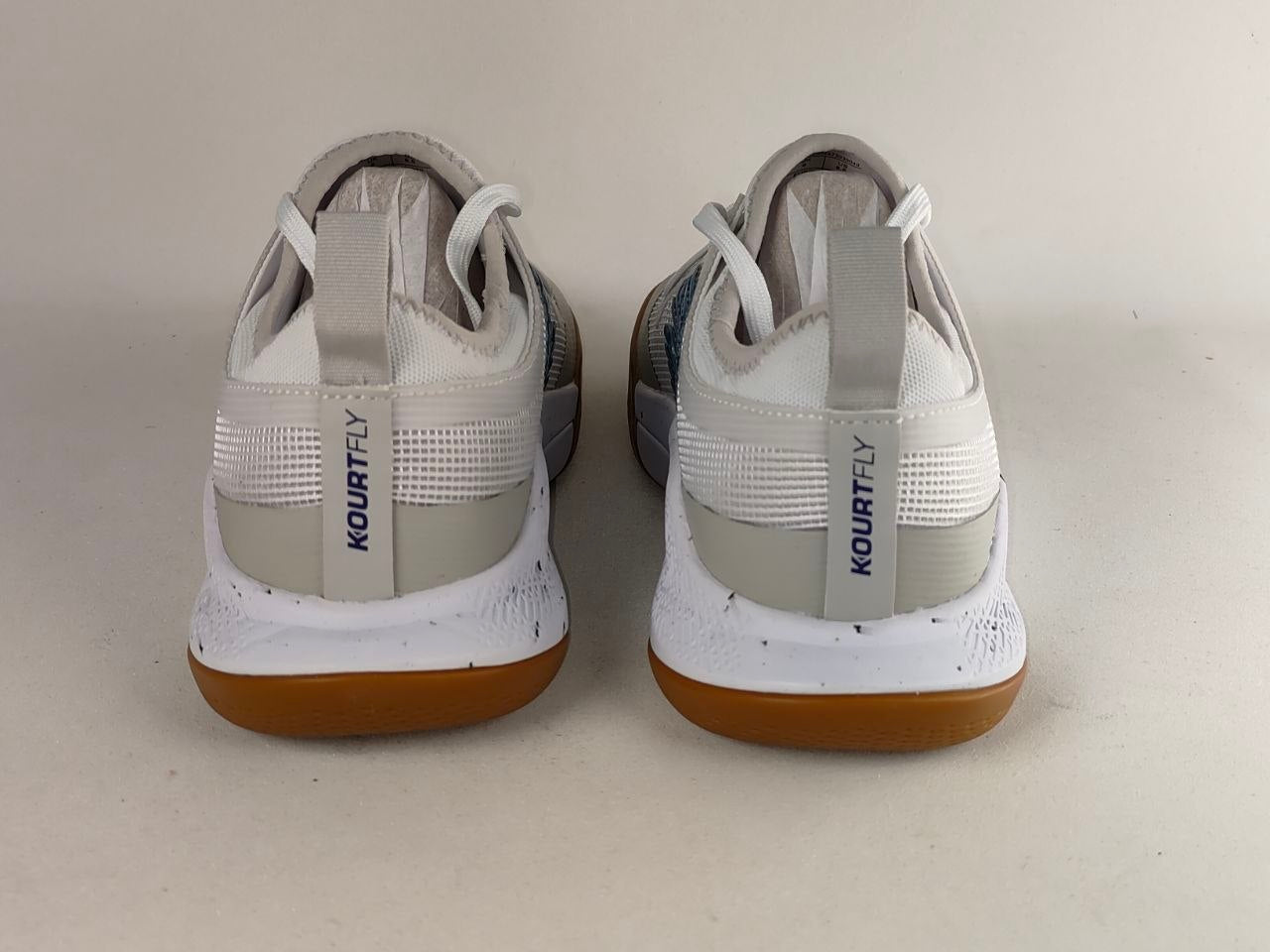 A pair of Kourtly basketball shoes shown from the back, featuring a white and light gray upper with a distinctive gum brown outsole.