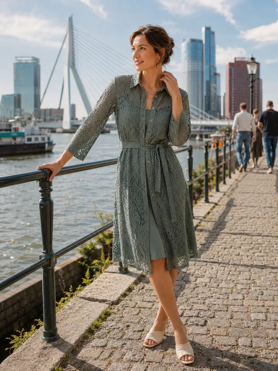 Woman in a green dress standing by a waterfront with a city skyline in the background