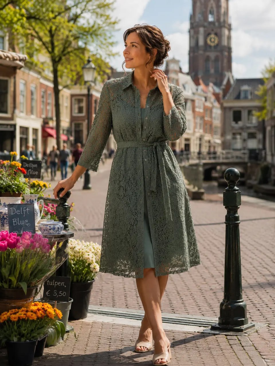 Woman in a green dress walking along a street with flowers and a clock tower in the background