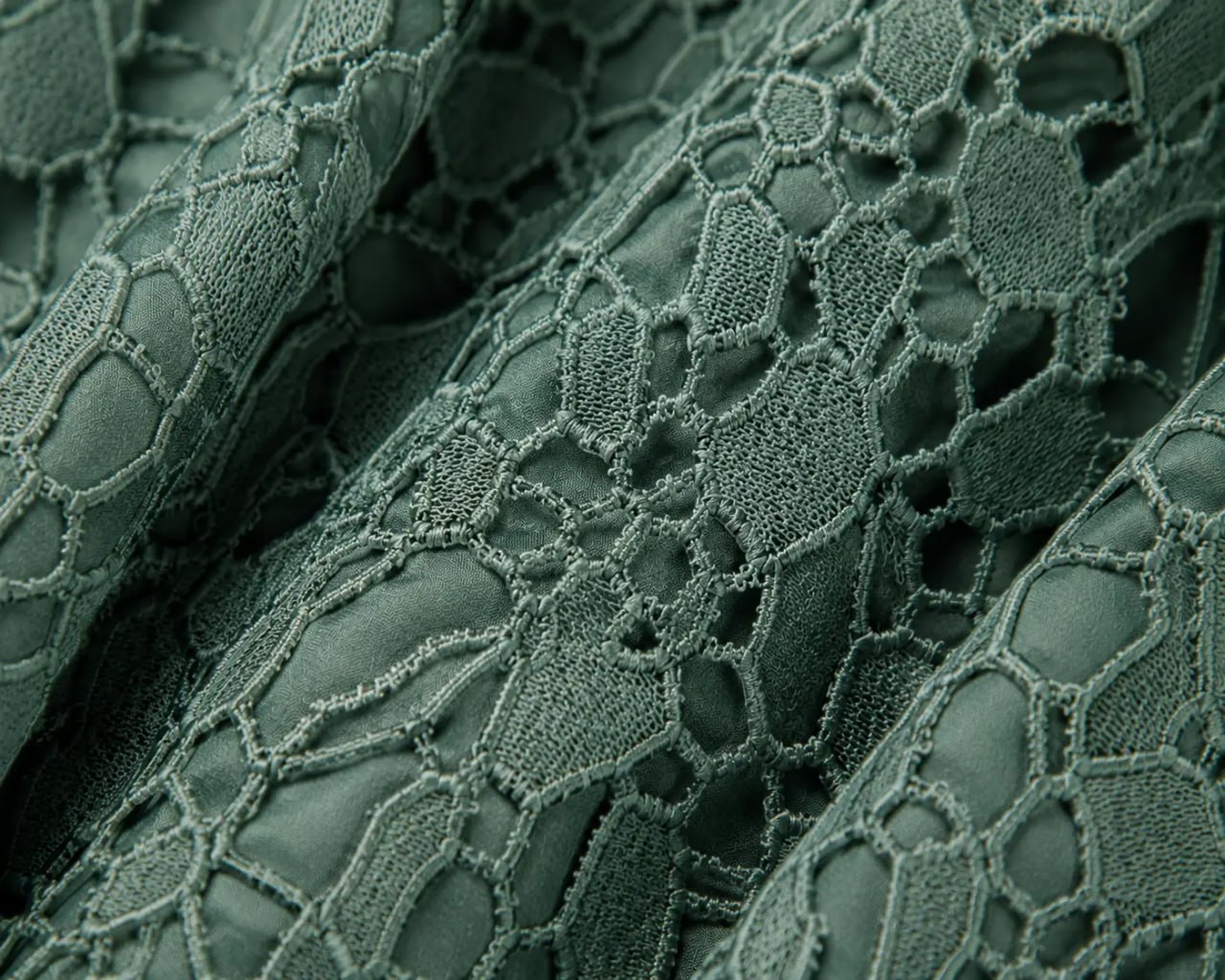 Close-up of textured green fabric with a lace-like pattern