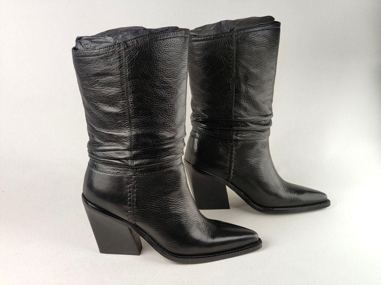 A pair of black leather mid-calf boots with pointed toes and block heels, shown against a plain light gray background.