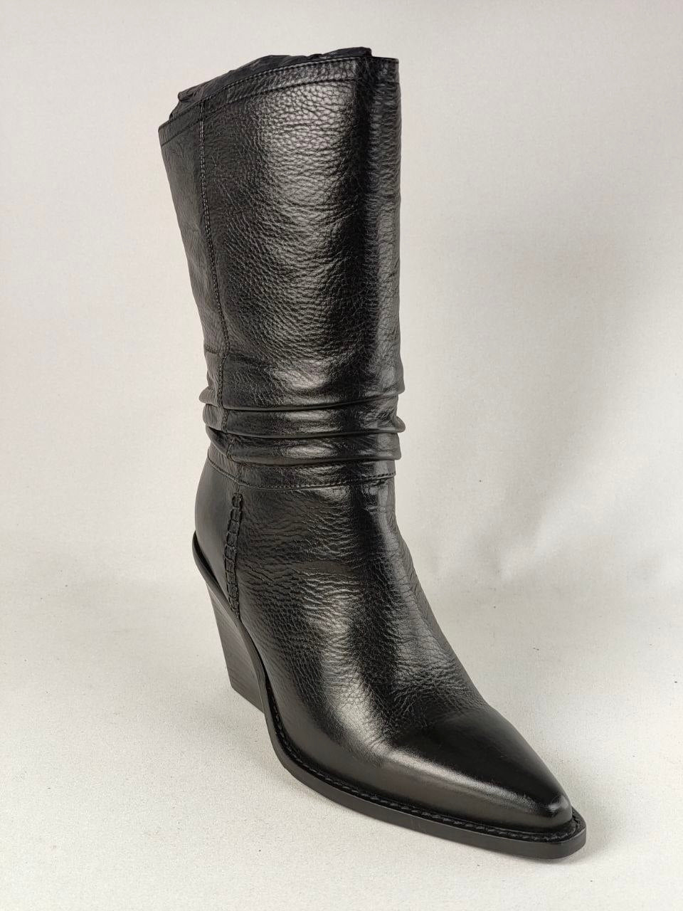 A single black leather mid-calf boot with a pointed toe and a low wedge heel, photographed against a light gray studio background.