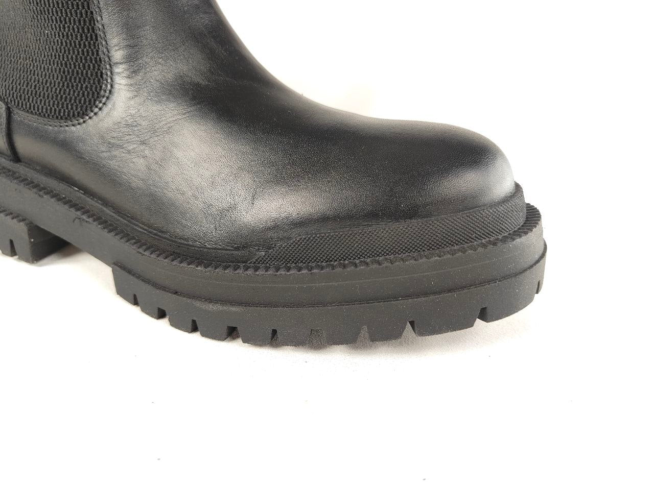 Close-up of a black leather Chelsea boot showing the side panel, toe, and rugged lug sole against a white background.