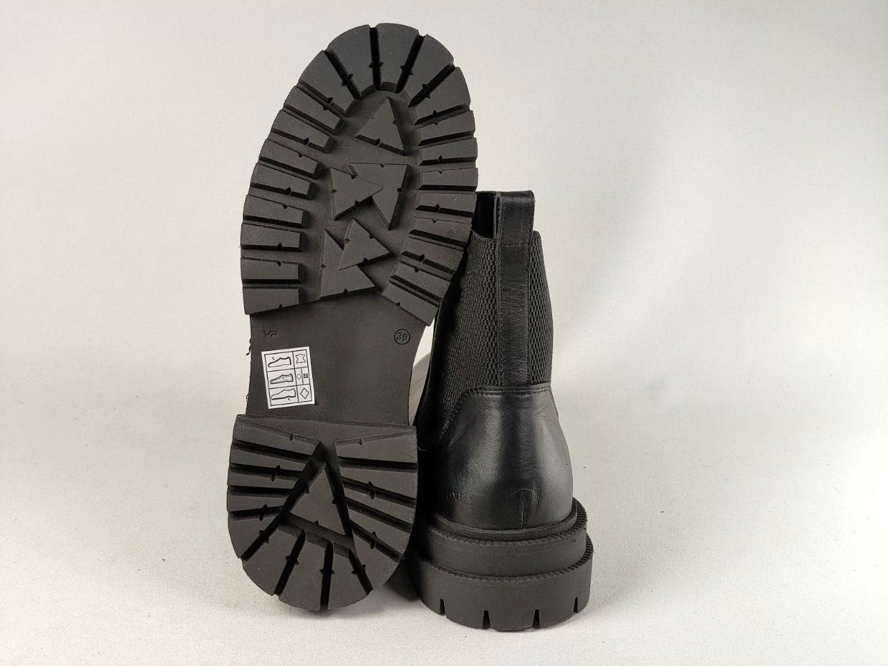 A pair of black ankle boots shown from the back, with one boot standing upright and the other tilted to display its textured treaded sole against a light gray background.