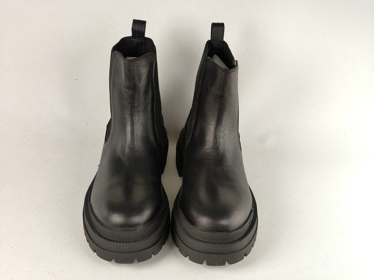 A pair of black leather Chelsea boots with chunky lug soles, photographed from the front against a plain white background.