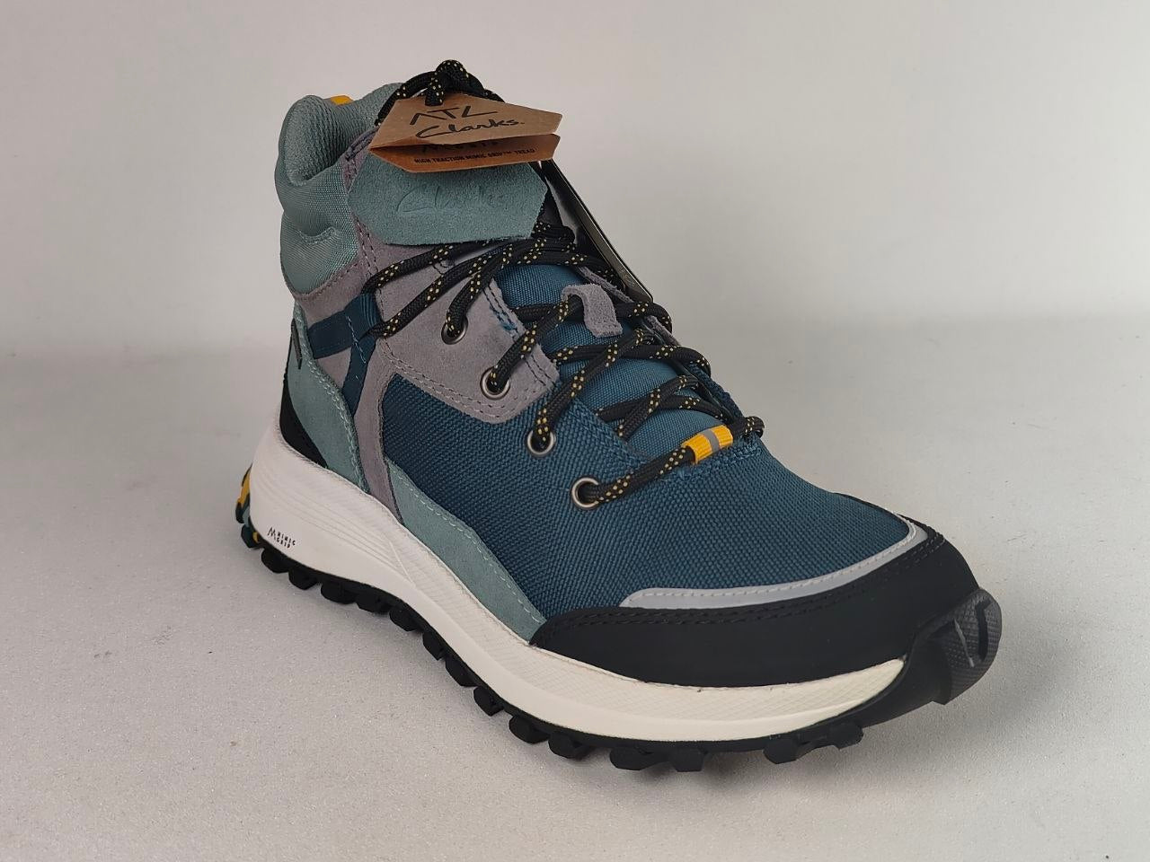 A single mid-cut hiking boot in slate blue, gray, and black with a white midsole and small yellow accents, shown on a light gray background.