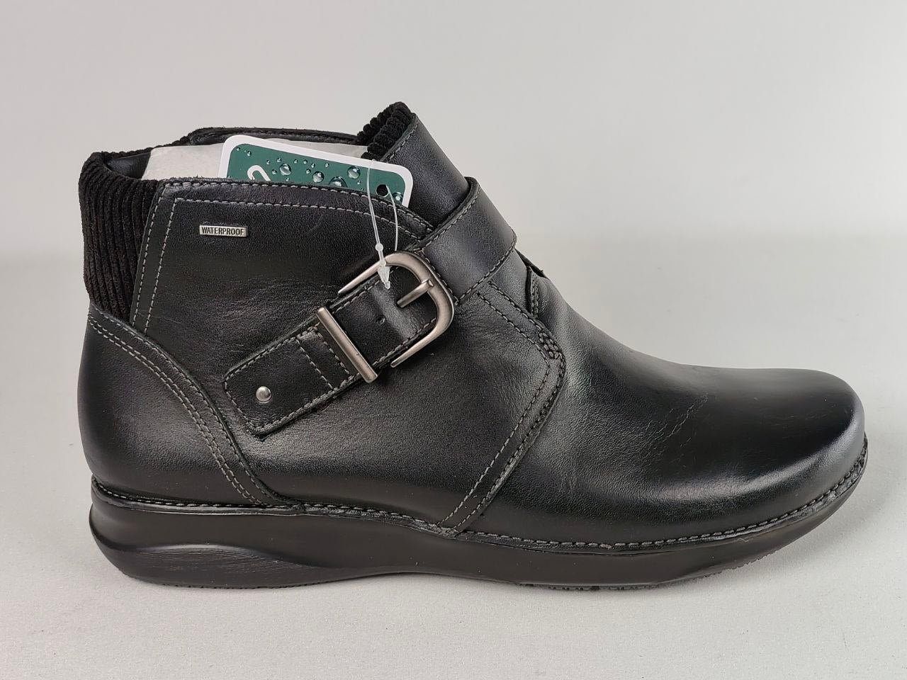 A black leather ankle boot with a buckle strap closure, black ribbed knit collar, and a low wedge heel, shown against a light gray background.