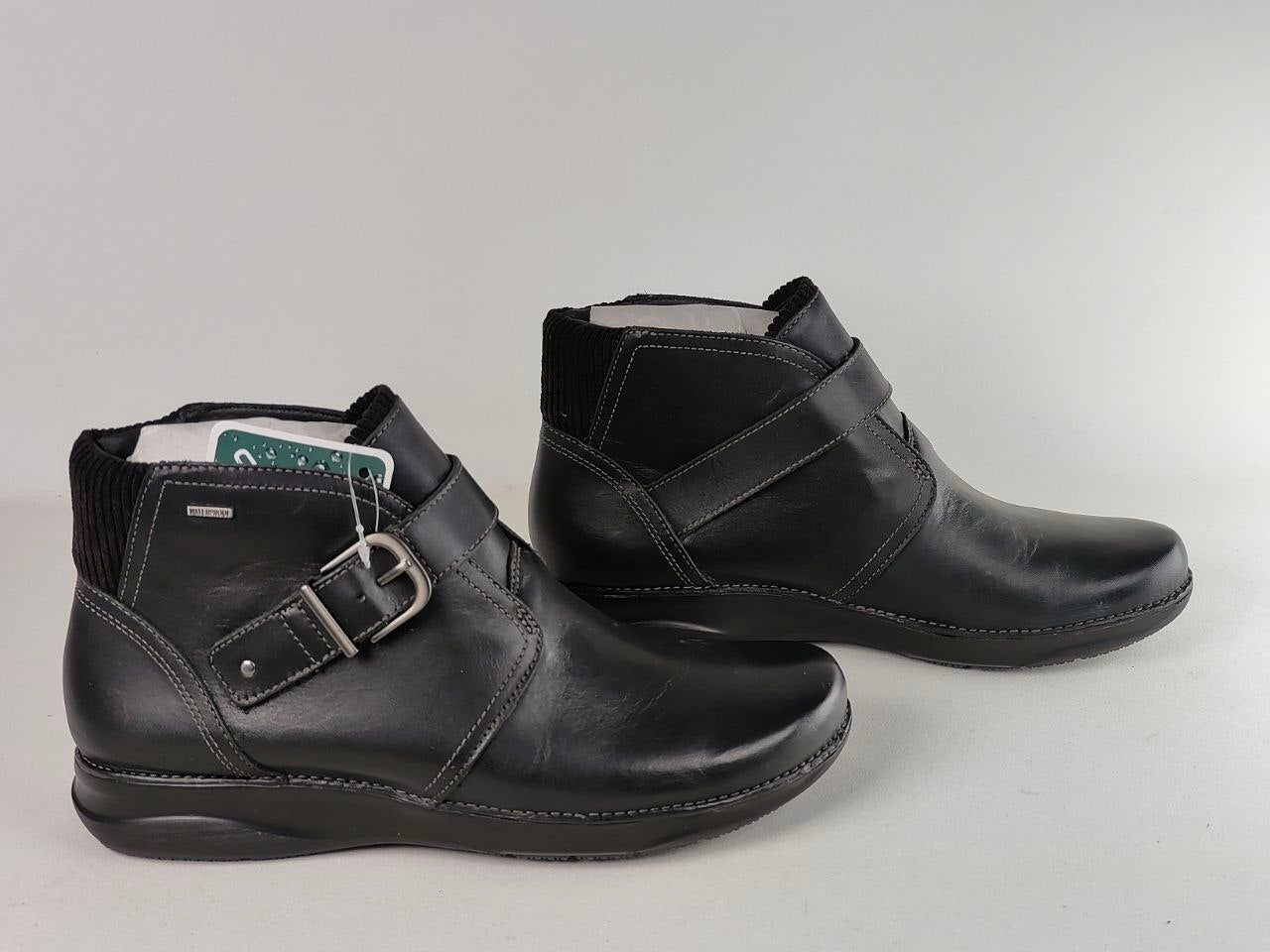 A pair of black leather ankle boots with buckle straps, shown on a light gray background.
