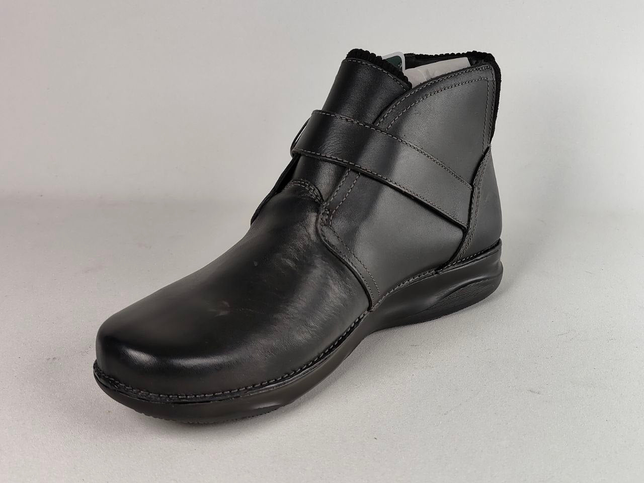 A single black leather ankle boot with a wide strap across the instep, photographed on a neutral light gray background.