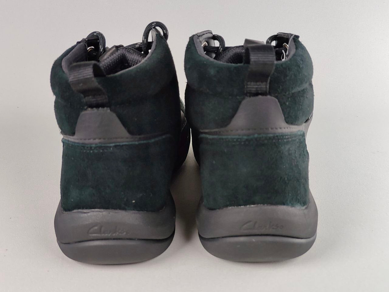 Pair of green high-top sneakers with black soles on a light gray background
