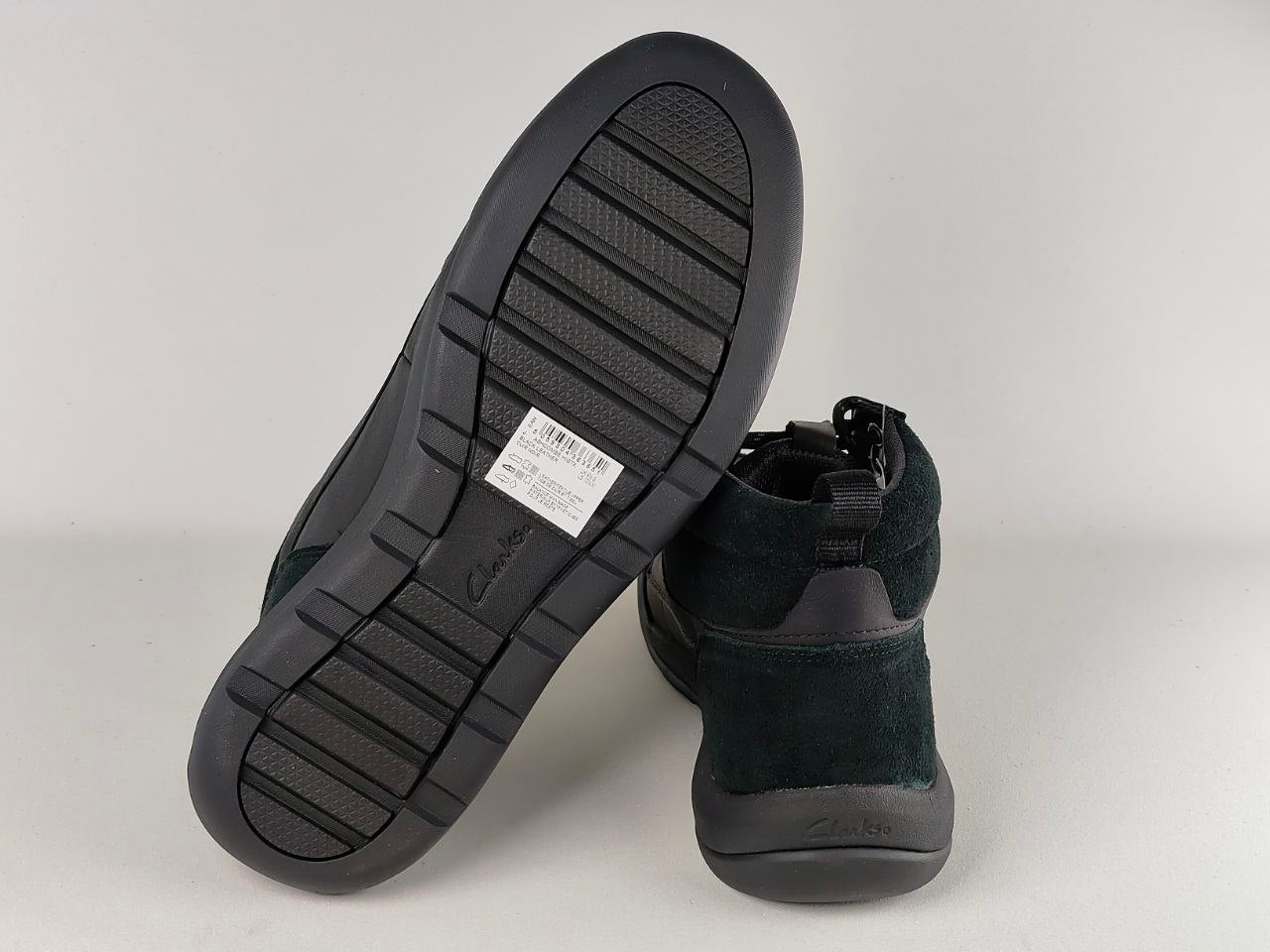 Black boots with a focus on the sole and brand label on a light gray background