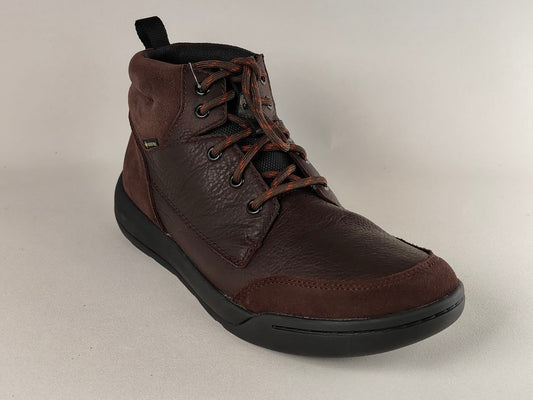 Brown leather boot with black sole on a light gray background