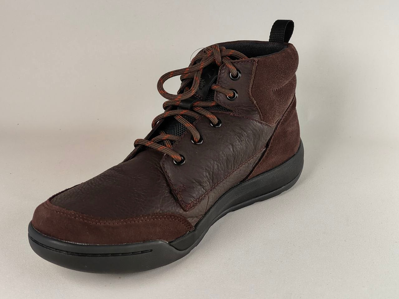 Brown leather boot with black sole on a light gray background