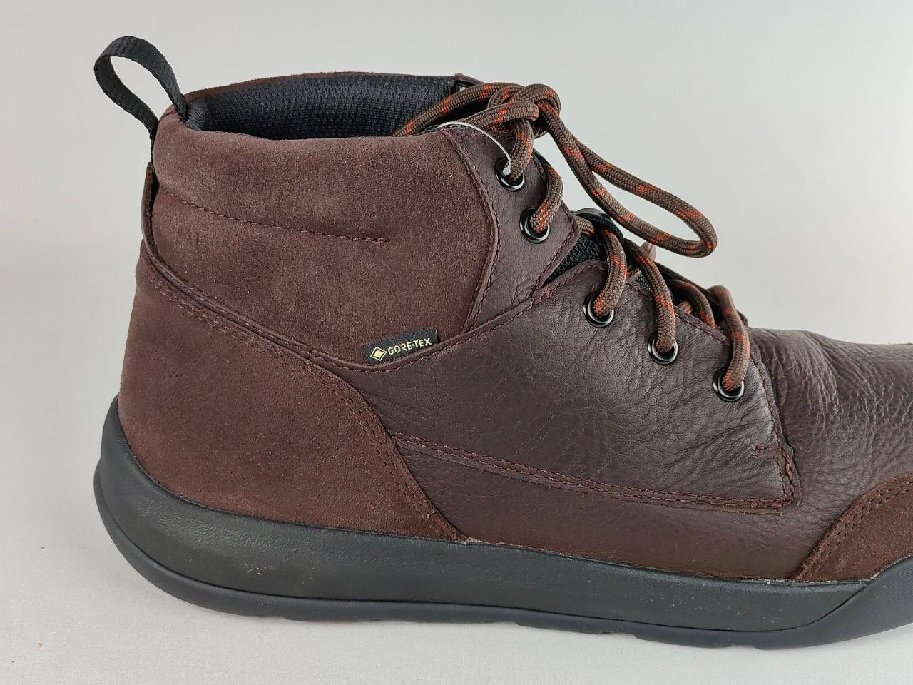 Brown leather boot with black sole on a light gray background