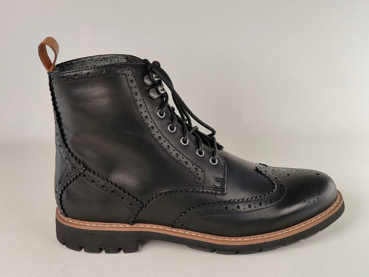 Black leather boot with brown sole on a light gray background