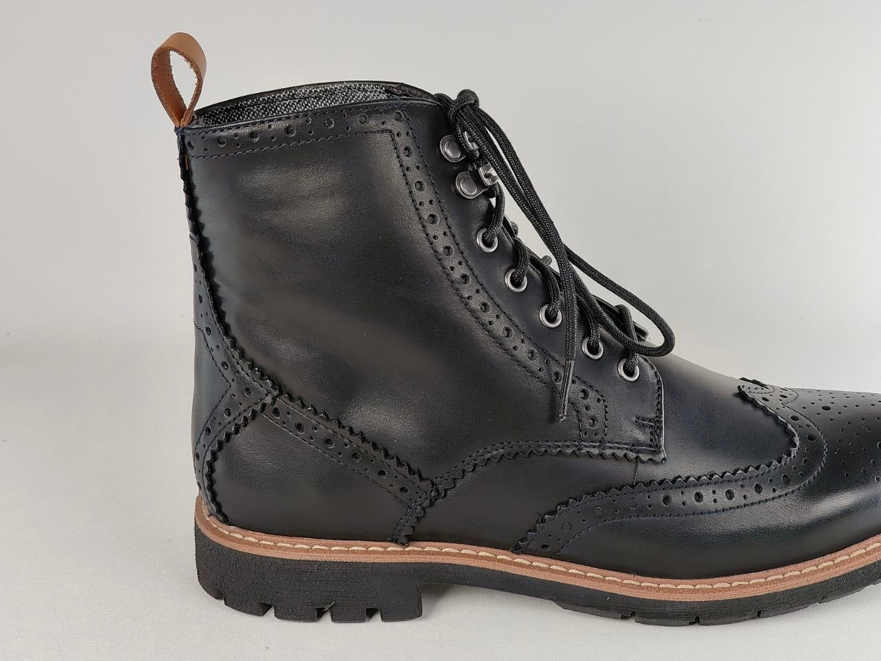 Black leather boot with brown sole on a light gray background