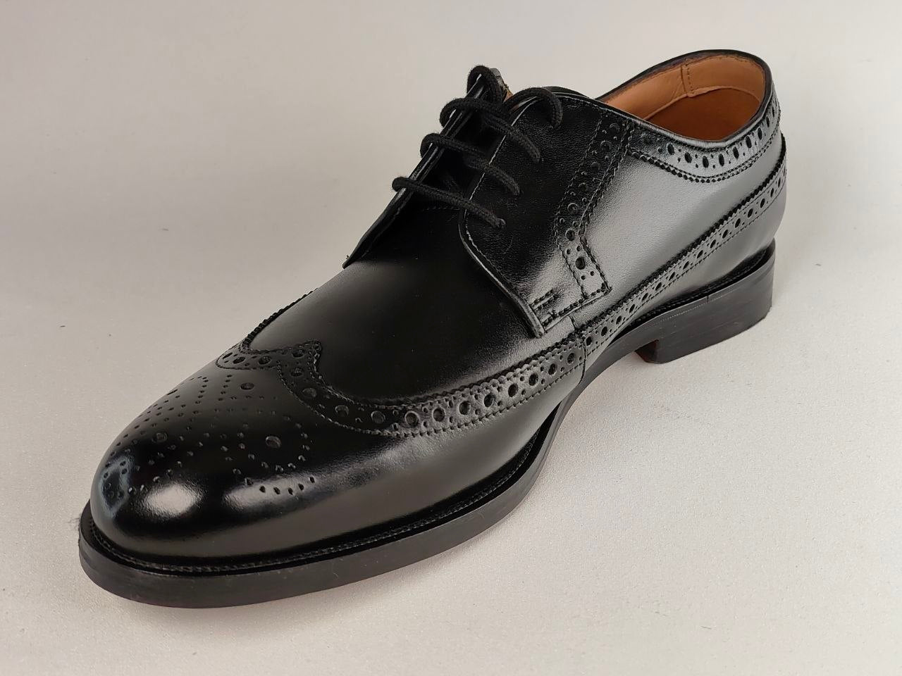 Black leather dress shoe on a light gray background