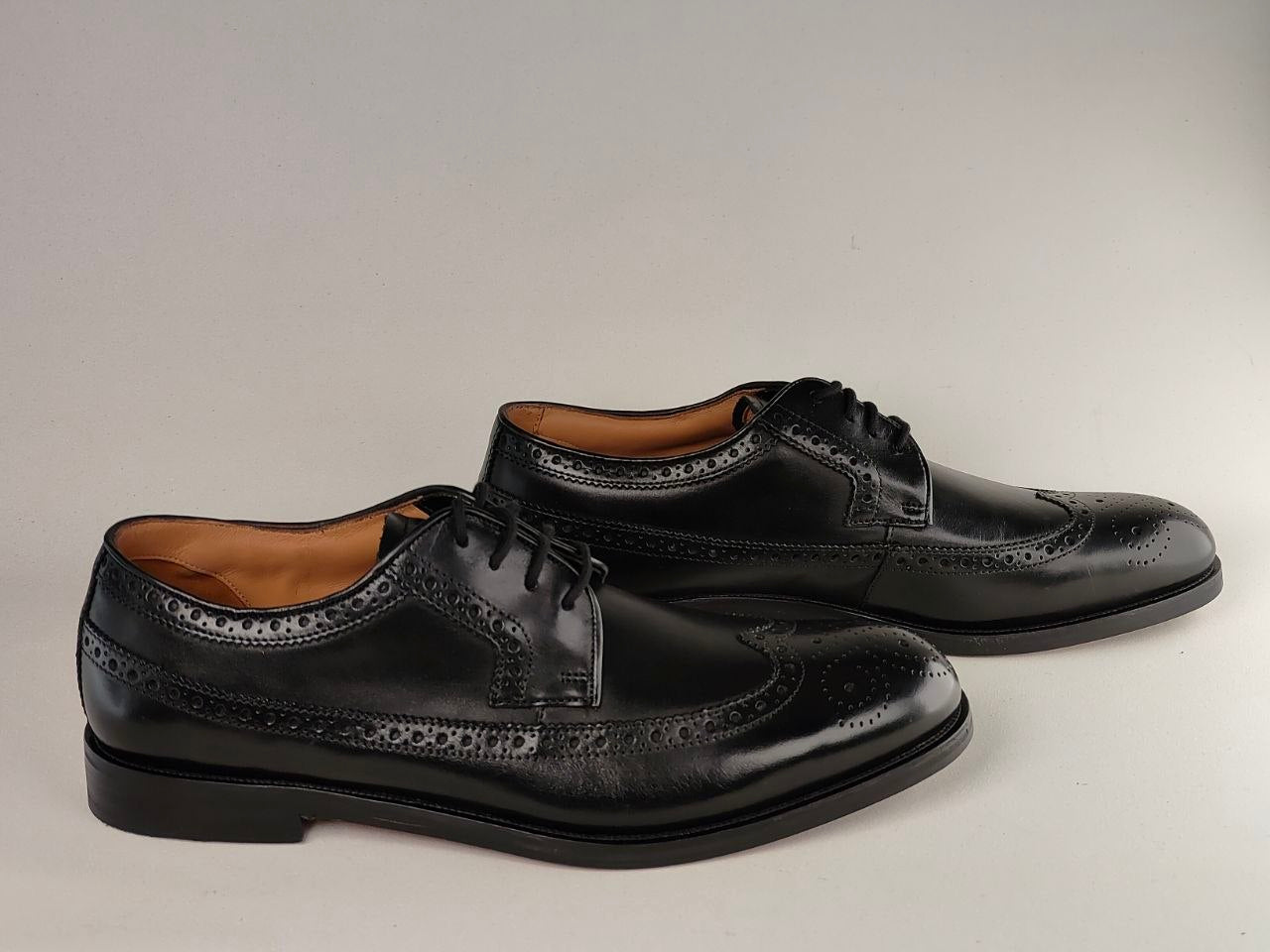 Pair of black leather dress shoes on a light gray background