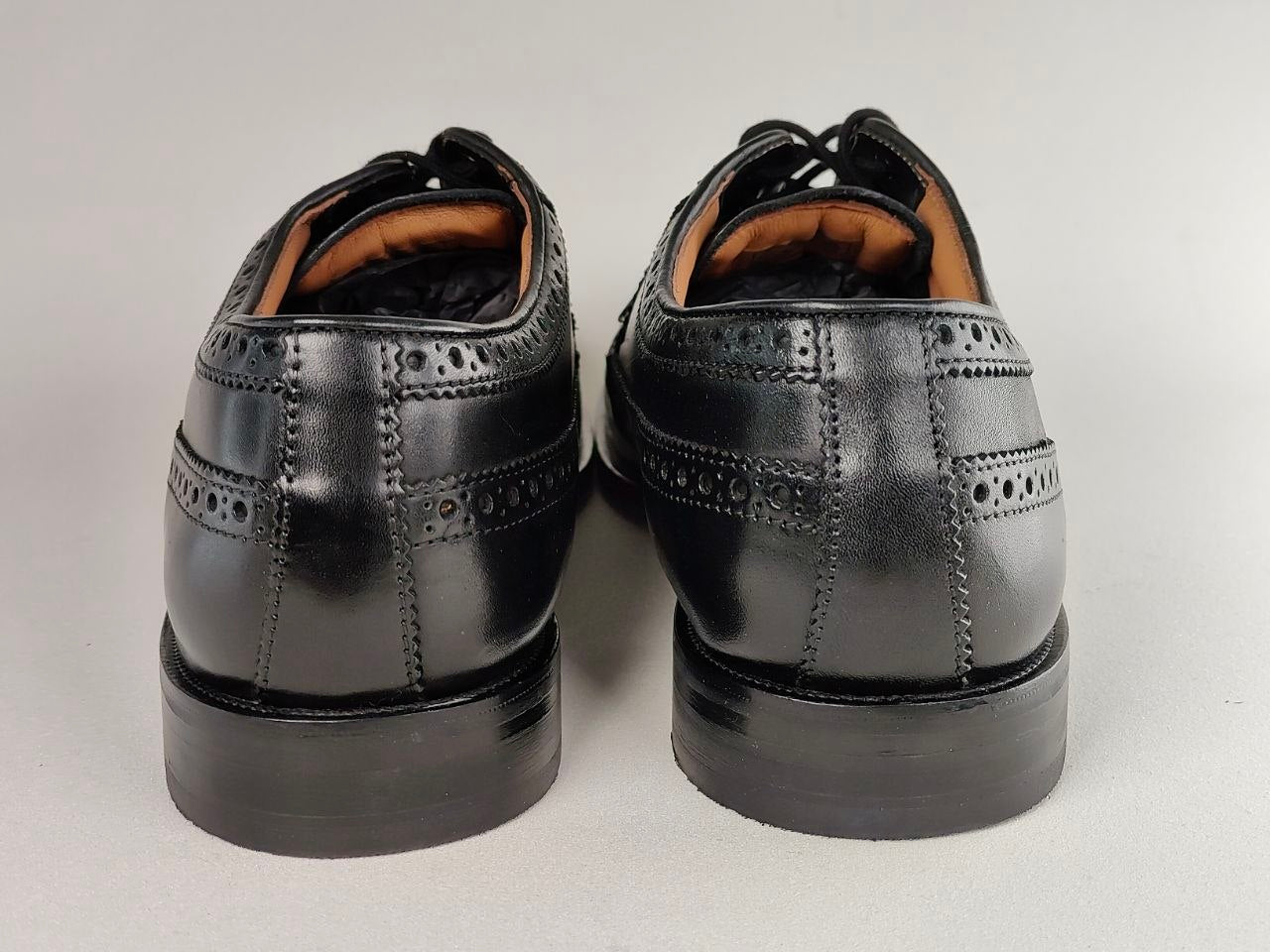 Pair of black leather dress shoes on a light gray background