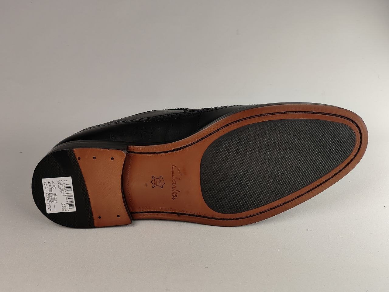 Black shoe sole with brown border and visible brand logo on a white background