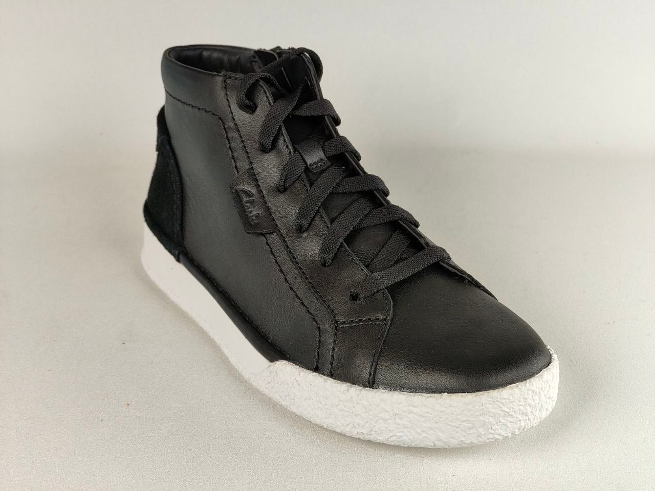 Black high-top sneaker with white sole on a light gray background