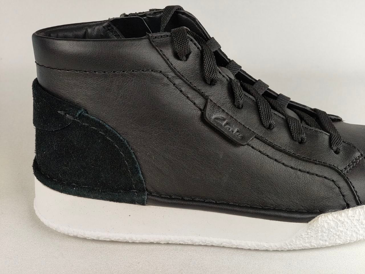 Black high-top sneaker with white sole on a light gray background