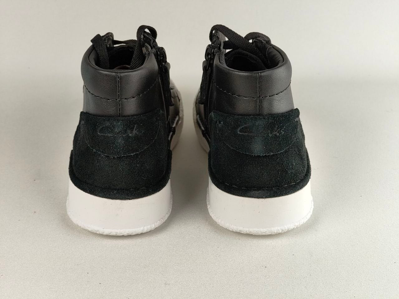 Black high-top sneakers with white soles on a light gray background
