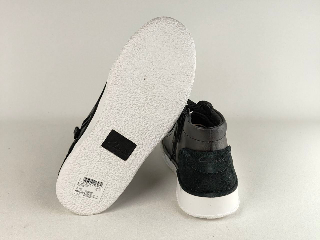 Black high-top sneakers with white soles on a light gray background